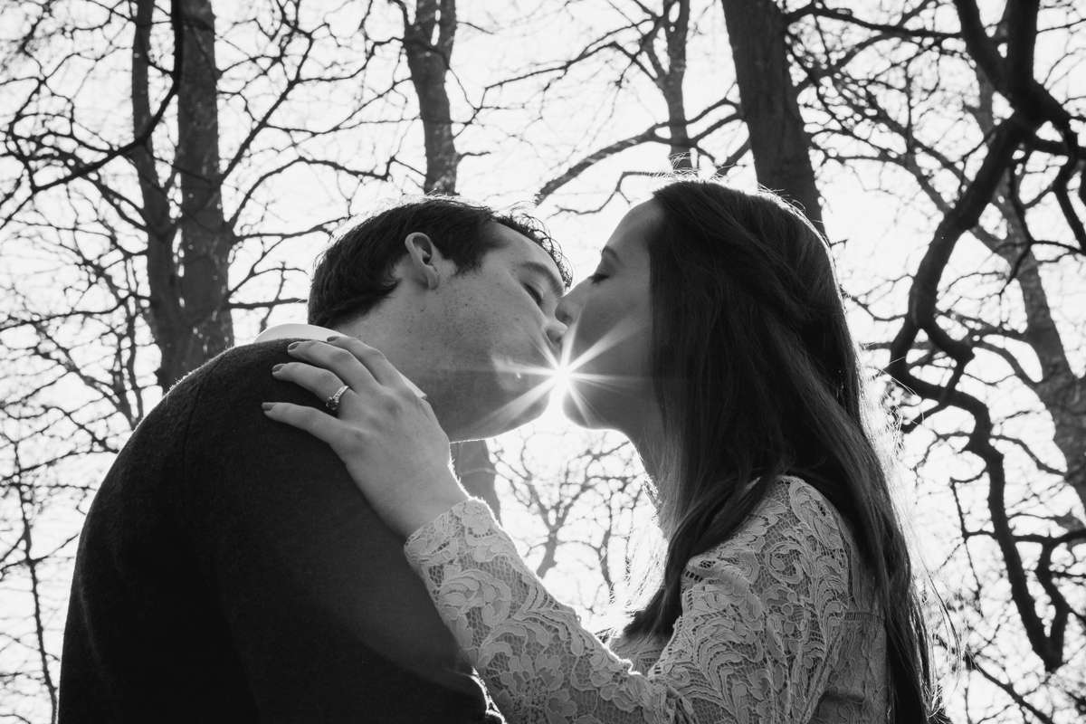 Black and white of a couple kissing with the sun between them