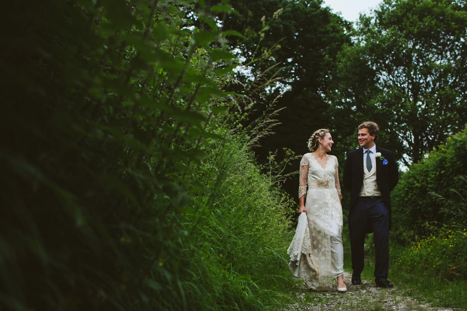 Bride and groom walking country lane